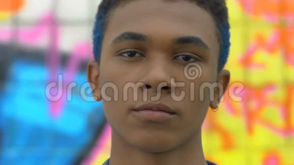 自信时尚的黑人青少年蓝发和耳环摆在相机上潮流视频的预览图