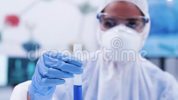 女科学家在试管里看着并拿着一种冒烟的蓝色液体视频的预览图