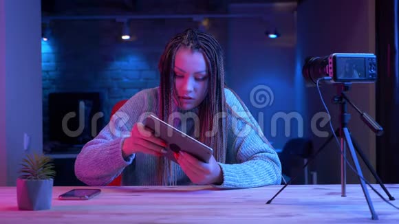 在平板电脑上玩电子游戏的有魅力的年轻女性博客写手的特写镜头让人情绪激动视频的预览图
