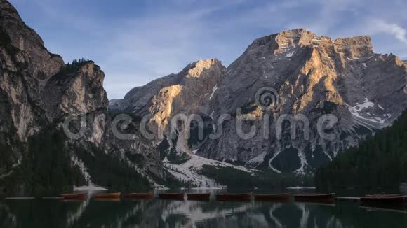 日落时分意大利南部蒂罗尔的白云岩阿尔卑斯山背景下的普拉格斯湖上的船只的时间流逝视频的预览图