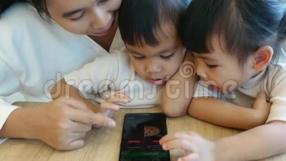 亚洲美丽的年轻母亲和她的小女儿喜欢在hom玩游戏或玩手机视频的预览图