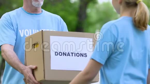 老年男性志愿者为年轻女性提供捐款箱慈善和支持视频的预览图