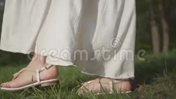 未被认出的可爱女人穿着惊人的白色连衣裙在公园里散步慢动作视频的预览图