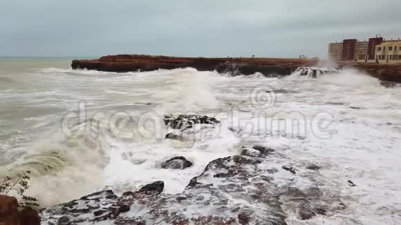 一股强大而强大的海浪缓慢地撞击着岩石海岸和大岩石4K视频的预览图