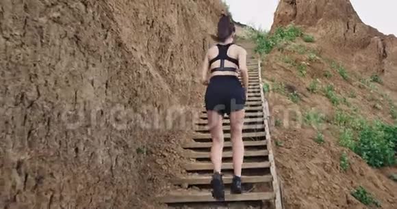 一个穿着黑色运动服的女孩在自然界的某些楼梯上跑步时保持健康视频的预览图
