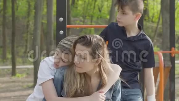 公园里许多孩子的母亲和她的儿子男孩们到处跑其中一个拥抱了那个女人大友好视频的预览图