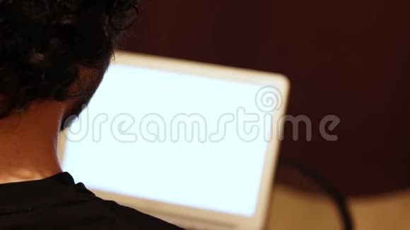 在家工作的人拿着白色屏幕的笔记本电脑从后面的视图关闭复制空间视频的预览图