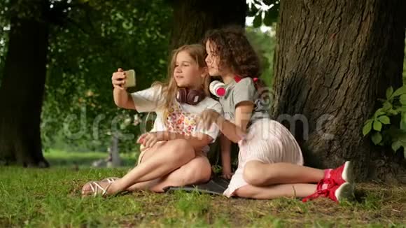 童年时光可爱的微笑小女孩喜欢在公园做一个自拍和听音乐与移动视频的预览图