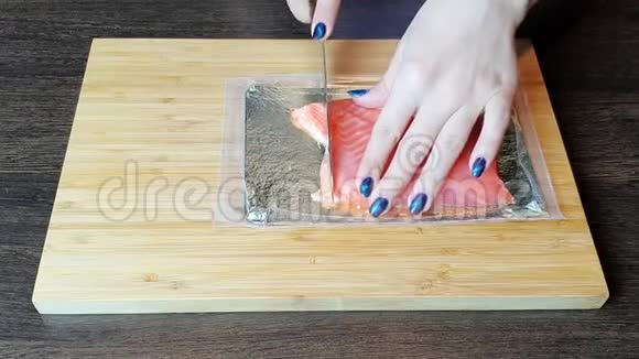 女孩用刀子在木板上切红鱼鳟视频的预览图
