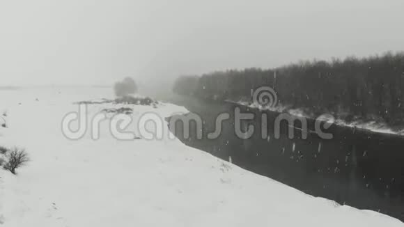 冬天的河流被树木和雪覆盖的河岸包围着视频的预览图