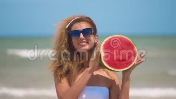 跳舞的女孩在美丽的大海的背景上有一个半多汁的西瓜快关门视频的预览图