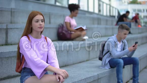 伤心的女学生独自坐在校园楼梯上不爱交际的青少年问题视频的预览图
