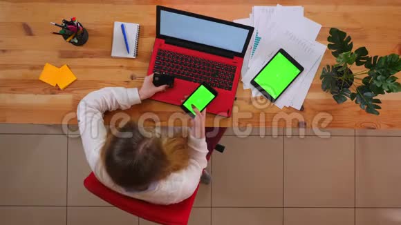 为年轻的高加索员工在手机上使用信用卡和带有绿色平板电脑进行网上购物的特写镜头视频的预览图