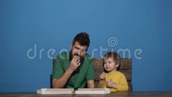 可爱的白种人男孩和男人吃披萨饿孩子吃披萨美味的食物家庭餐视频的预览图