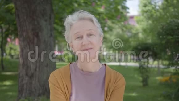 可爱的老妇人在绿色令人惊叹的公园里笑着白发的肖像可爱的成熟祖母躺在视频的预览图