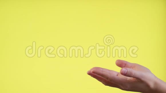 双手在黄色背景下试图捕捉美元钞票在缓慢移动中的下落视频的预览图