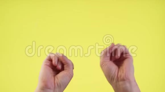 女人的手挥动着跳舞的手指拍打着音乐节奏的手势在工作室里的黄色背景上被隔离开来视频的预览图