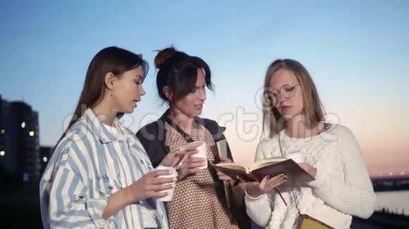 三个年轻女人喝咖啡读一本书视频的预览图