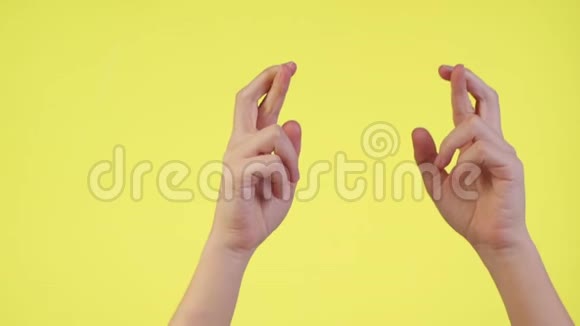 女人的双手交叉着手指等待着特殊的时刻让愿望在黄色的背景上被隔离视频的预览图