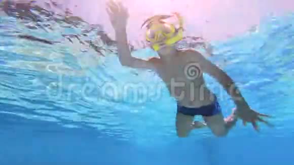 小男孩孩子带着黄色面具在游泳池里游泳水下录像视频的预览图