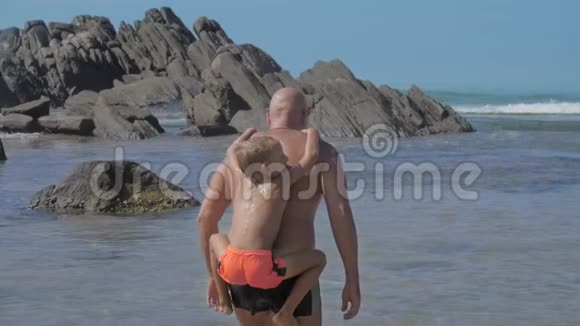 男孩挂在父亲的肩上花时间在海边视频的预览图