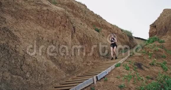 一个年轻的运动女子从山上的几个楼梯上跑下来视频的预览图