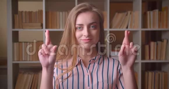 年轻漂亮的白种人女学生的特写镜头她的手指交叉着满怀希望地看着镜头视频的预览图