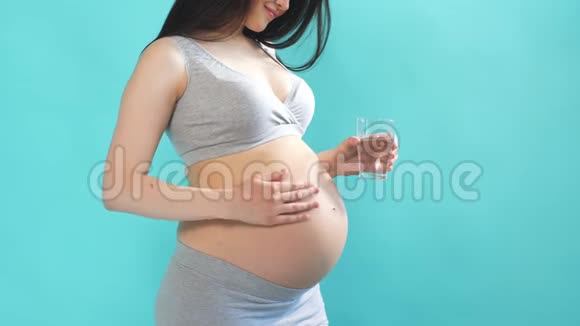 年轻的孕妇从杯子里喝着清爽的水视频的预览图