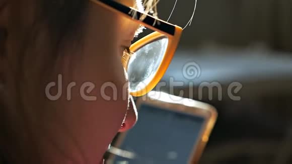 一位戴眼镜的年轻女士看着窗户附近的智能手机的侧视图视频的预览图