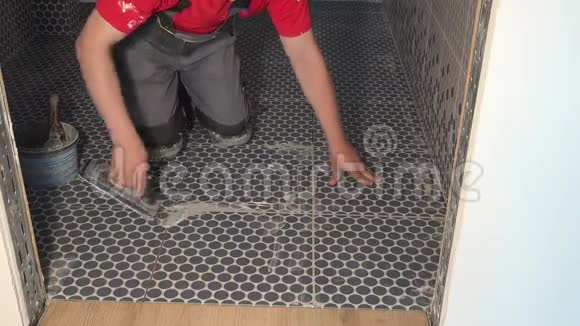 熟练工人在浴室的地砖上放赋格灌浆瓷砖视频的预览图