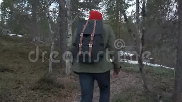 从后面看一个闲人在外面度过一天独自走在秋天的森林里带背包的男人享受安静视频的预览图