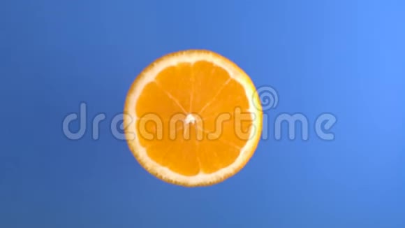 橙色鲜果落入蓝水液与旋转溅与滴在慢运动顶部拍摄视频的预览图