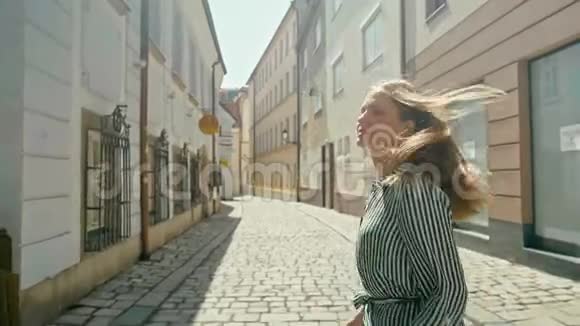 在布拉迪斯拉发的漂亮街道上快乐的女游客散步转身微笑视频的预览图