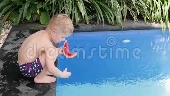 男孩在院子里的水池边吃西瓜小孩在度假时吃水果视频的预览图