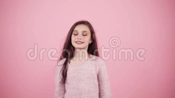 快乐美丽的年轻女孩在粉红色的背景上玩甜甜圈可爱的长发女孩与甜甜圈关闭视频的预览图
