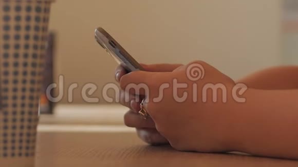 年轻的女人坐在咖啡馆里用手机打字网店的概念视频的预览图