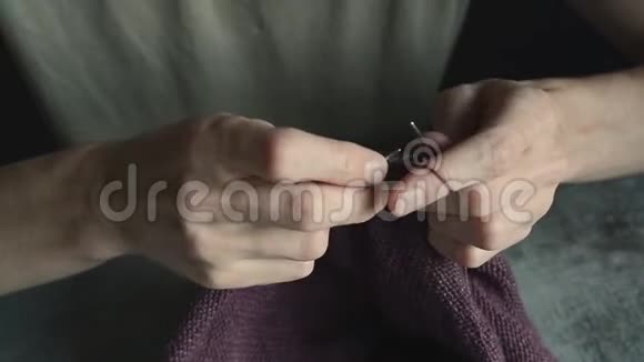成年年轻人用灰色金属针和暗红色棉线编织手视频的预览图