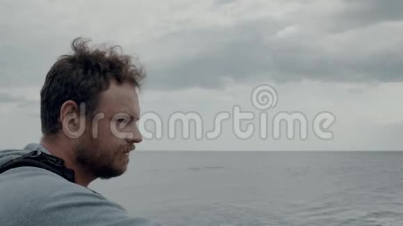 一个留胡子的人在海和云的背景下的肖像用相机拍摄大海的照片4k4k视频视频的预览图