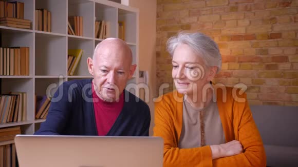 高加西亚夫妇坐在家中愉快地看着笔记本电脑视频的预览图