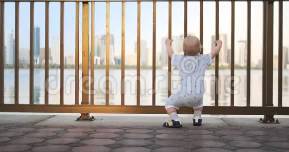 舞动着欢快的欧洲男孩的后视镜靠近栅栏抓住栏杆站着跳舞看着视频的预览图