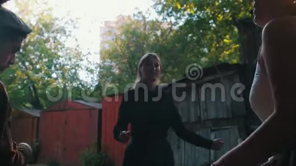 女人站在乡间别墅附近跳舞和娱乐一个男人玩巴拉莱卡明亮的阳光视频的预览图