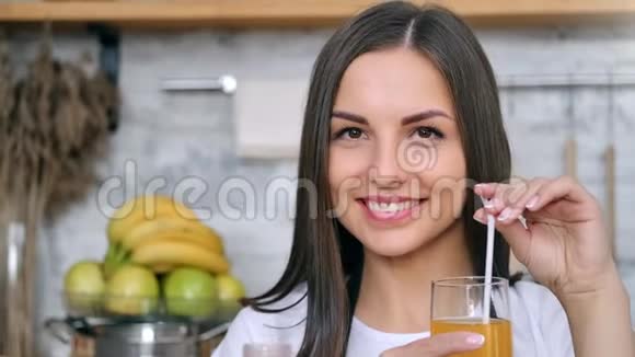女孩微笑着用一杯具有积极情感的天然橙汁摆姿势的特写肖像视频的预览图