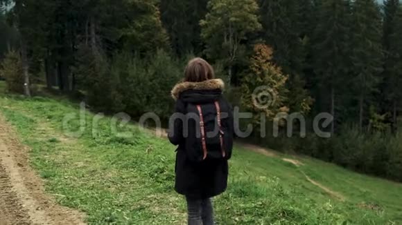 镜头跟随年轻女孩远足者走在户外并展示了手上的山脉景观视频的预览图