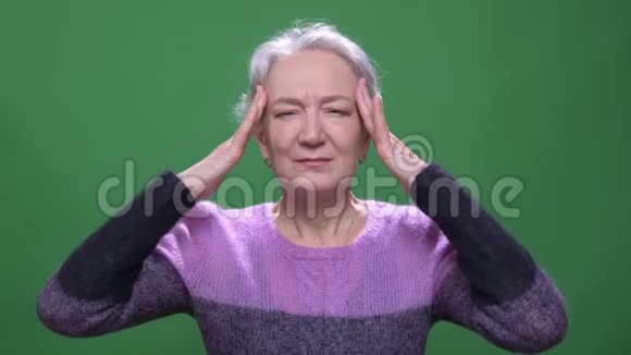 老年灰发妇女的肖像患有喉咙痛和头痛孤立于绿色染色背景视频的预览图