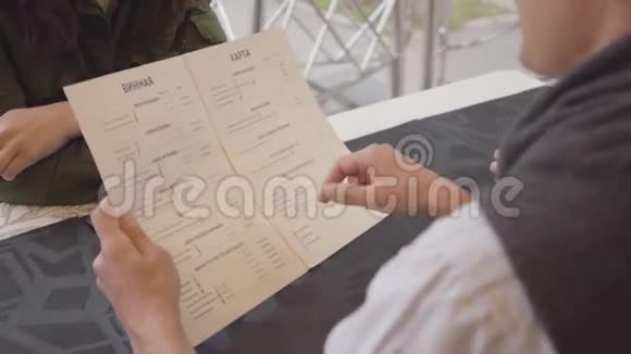 在咖啡馆或餐馆里阅读俄语菜单选择食物的朋友在咖啡馆里开会的人视频的预览图