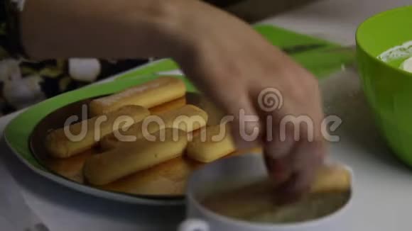 一个女人用萨沃亚迪饼干做蛋糕把饼干蘸上糖浆放在基质上视频的预览图