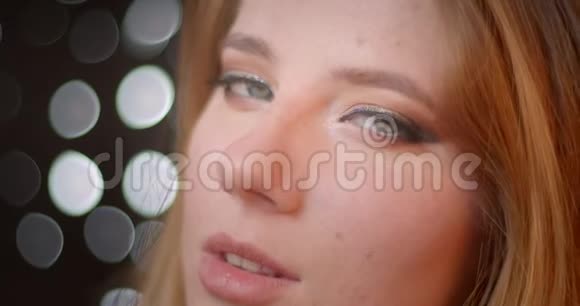 性感的金发模特生动和闪亮的化妆手表进入相机与调情的目光在bokeh背景视频的预览图