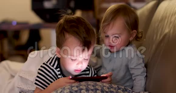 孩子们在沙发上看智能手机视频的预览图
