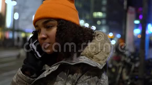 美国黑人少女少女夜以继日在城市大街上用手机聊天视频的预览图