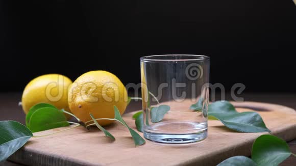 人手把柠檬汁从水罐里倒入木板上的玻璃杯里快关门视频的预览图
